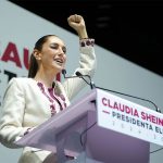 President-elect Claudia Sheinbaum raises a fist as she speaks at a podium.