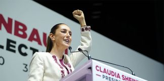 President-elect Claudia Sheinbaum raises a fist as she speaks at a podium.