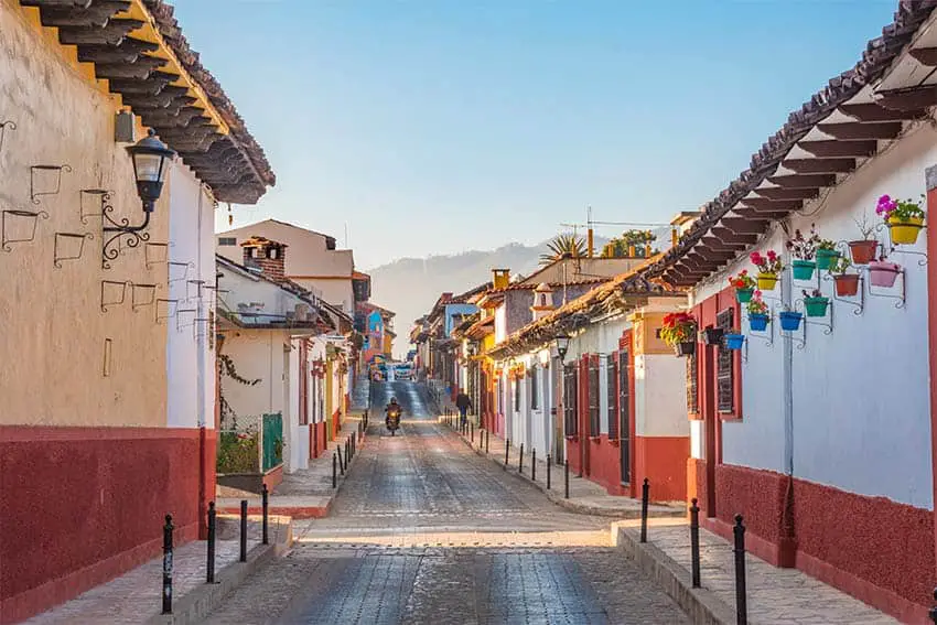 Empty street with picturesque historic houses on both sides in San Cristobal de las Casas, Chiapas, with a single motorcycle in the distance