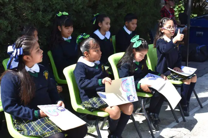 Mexican schoolchildren sitting on chairs outside