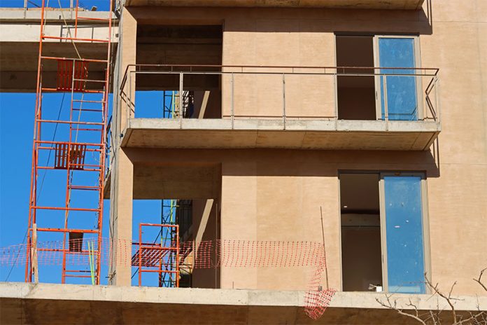 Red scaffolding and adobe stone frames of an apartment block being built in Los Cabos, Mexico.