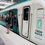 An attendant stands outside the Maya Train, a major Mexican rail project, to welcome passengers