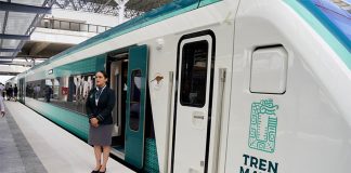 An attendant stands outside the Maya Train, a major Mexican rail project, to welcome passengers