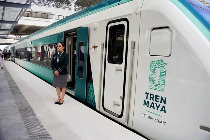 An attendant stands outside the Maya Train, a major Mexican rail project, to welcome passengers