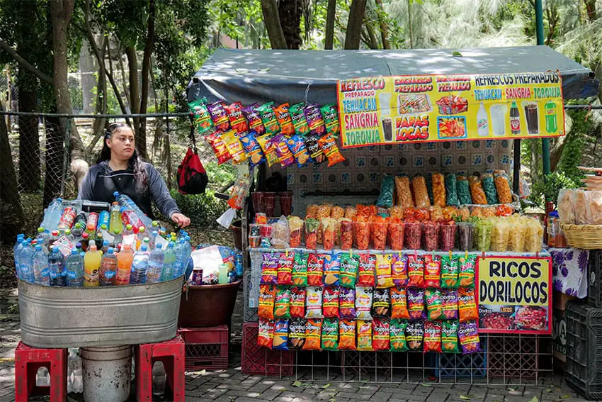 A woman sells drinks and snacks at a street stall