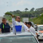 Father Baxin of Santa Ana church in Soconusco, Veracruz, stood in the back of a pick-up truck sprinkling holy water along federal Highway 180.