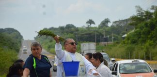 Father Baxin of Santa Ana church in Soconusco, Veracruz, stood in the back of a pick-up truck sprinkling holy water along federal Highway 180.