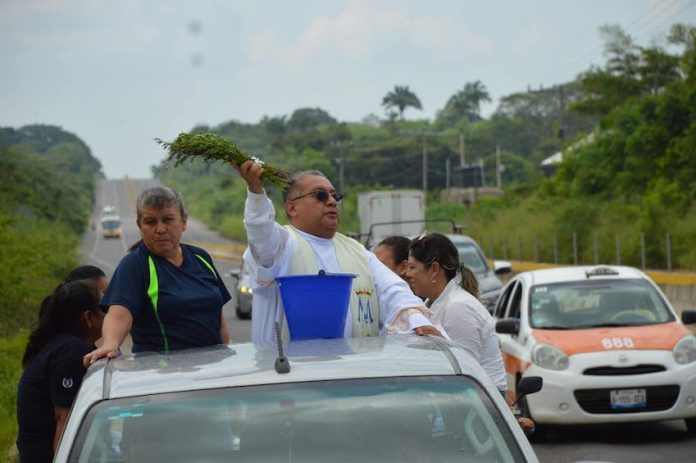 Father Baxin of Santa Ana church in Soconusco, Veracruz, stood in the back of a pick-up truck sprinkling holy water along federal Highway 180.