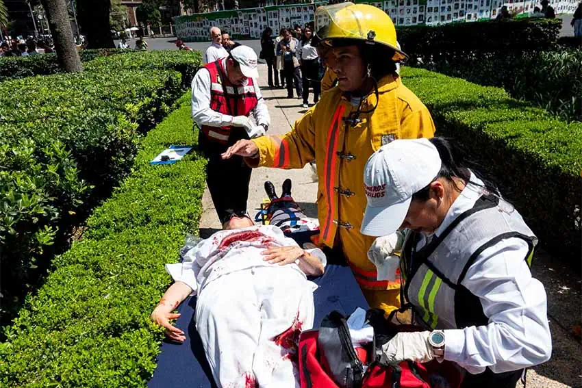 Mexico City emergency personnel stand over a stretcher and simulate tending to a quake victim using a dummy made to look like it has a severed leg and a deep gash in its chest