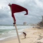 A red warning flag for strong current standing on an empty Gaviota Azul beach in Cancun, Mexico