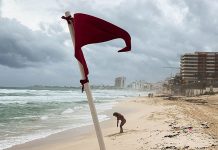 A red warning flag for strong current standing on an empty Gaviota Azul beach in Cancun, Mexico