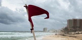 A red warning flag for strong current standing on an empty Gaviota Azul beach in Cancun, Mexico