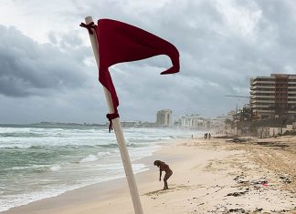 A red warning flag for strong current standing on an empty Gaviota Azul beach in Cancun, Mexico