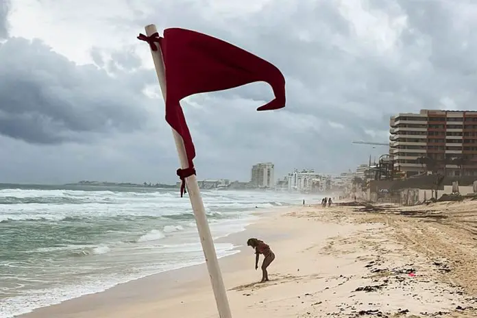 A red warning flag for strong current standing on an empty Gaviota Azul beach in Cancun, Mexico