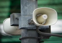 White megaphone-style loudspeakers mounted high on a metal pole in Mexico City, set up to alert citizens during earthquakes