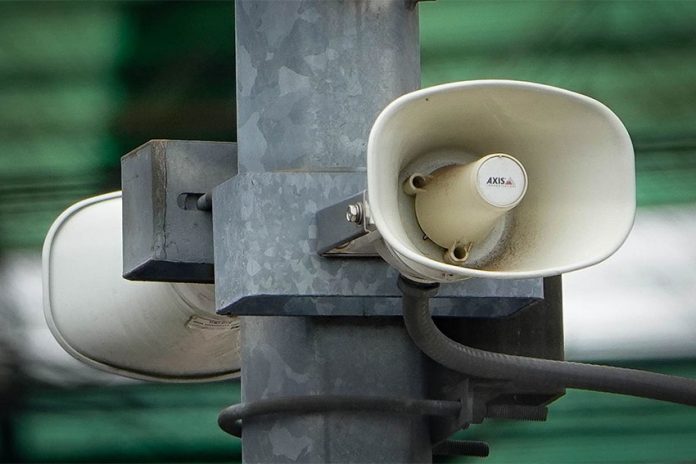 White megaphone-style loudspeakers mounted high on a metal pole in Mexico City, set up to alert citizens during earthquakes