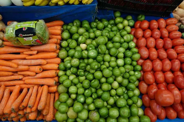 A farmer's market display of hundreds of carrots, tomatillos and tomatoes