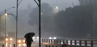 Resident of Mexico City walking with an umbrella near a highway in heavy rains and fog.