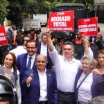 Mexican senators in suits hold signs reading "rechazo total" while standing in front of judicial reform protesters in the streets of Mexico City