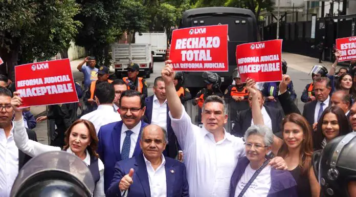 Mexican senators in suits hold signs reading "rechazo total" while standing in front of judicial reform protesters in the streets of Mexico City