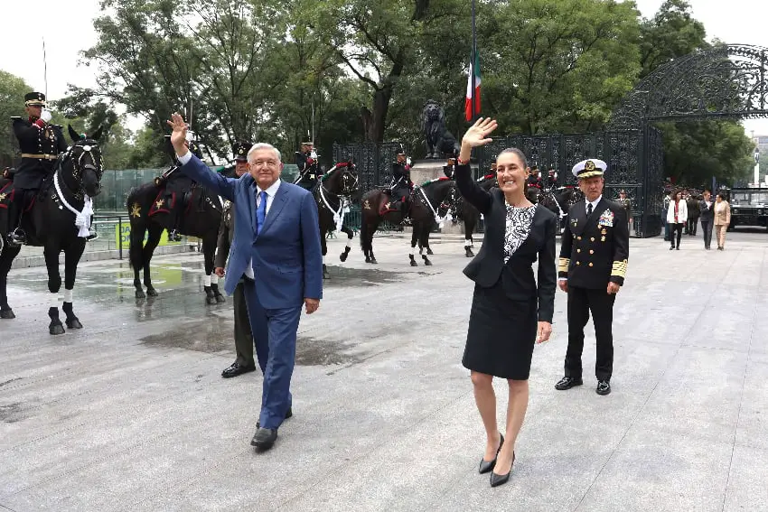 AMLO and Claudia Sheinbaum wave at a civic event