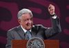 Mexico's President Lopez Obrador standing at the presidential press conference podium with his fist raised