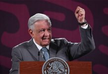 Mexico's President Lopez Obrador standing at the presidential press conference podium with his fist raised