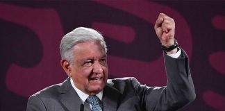 Mexico's President Lopez Obrador standing at the presidential press conference podium with his fist raised