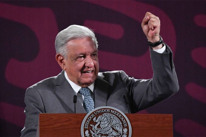 Mexico's President Lopez Obrador standing at the presidential press conference podium with his fist raised