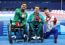 Mexican swimmer Ángel Camacho displays his medal, sitting next to the first and third place winners of the 50-meter backstroke S4 category.