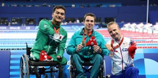 Mexican swimmer Ángel Camacho displays his medal, sitting next to the first and third place winners of the 50-meter backstroke S4 category.