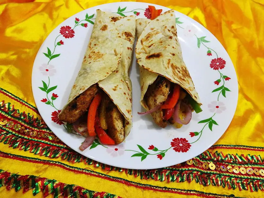 A plate of fajitas wraps, a Tex-Mex dish, on a yellow tablecloth.