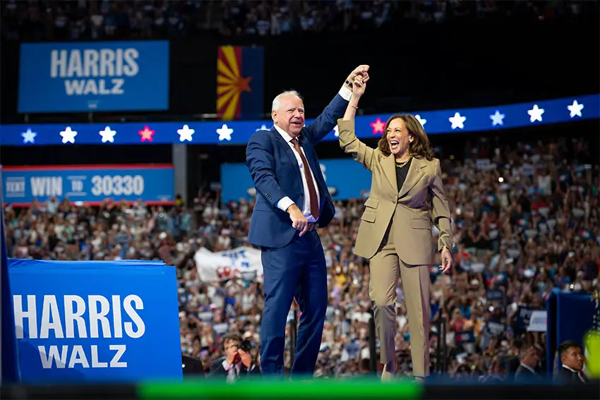 Tim Walz y Kamala Harris en la convención nacional del Partido Demócrata parados en el escenario, tomados de la mano en alto y sonriendo