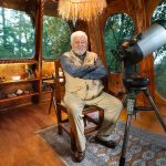 Mexican ufologist Jaime Maussan sits in his living room with a telescope