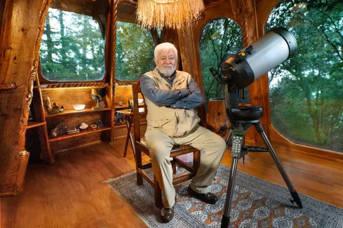 Mexican ufologist Jaime Maussan sits in his living room with a telescope