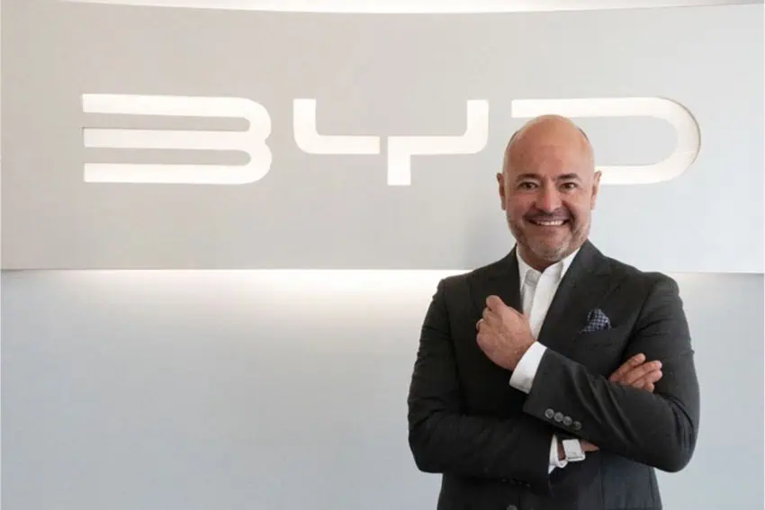 El director general de BYD para México, Jorge Vallejo, sonriendo y de pie frente a un logo de BYD incrustado en una pared.