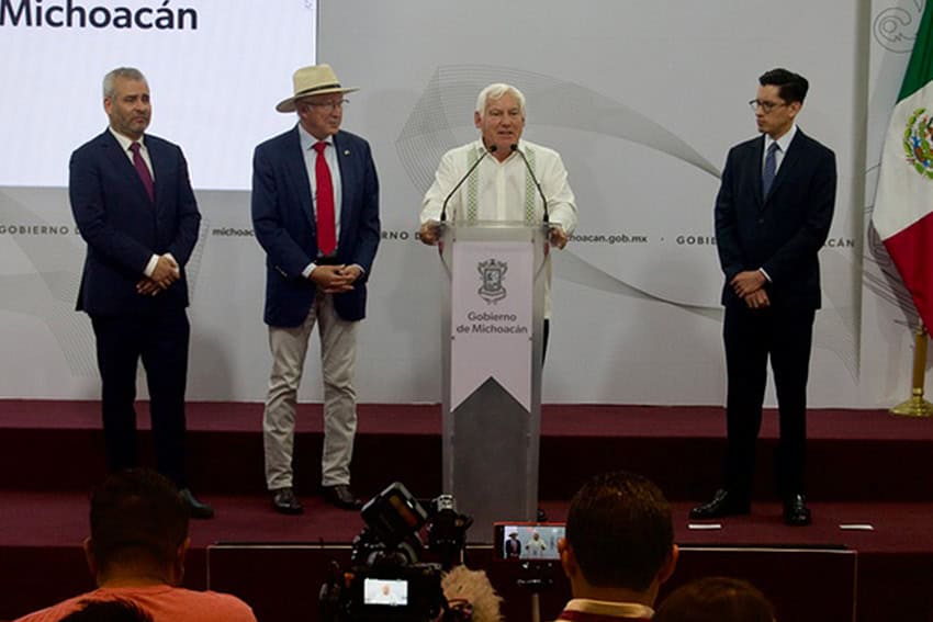 Mexican Agriculture Minister Victor Villalobos stands behind a podium speaking to the press, flanked by three other men, including U.S. Ambassador to Mexico Ken Salazar, to Villalobos' right.