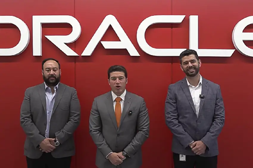 Three men standing in front of a wall with the logo for Oracle.