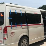 A white 15-passenger van in Tulum with people exiting it.