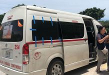 A white 15-passenger van in Tulum with people exiting it.