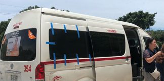 A white 15-passenger van in Tulum with people exiting it.