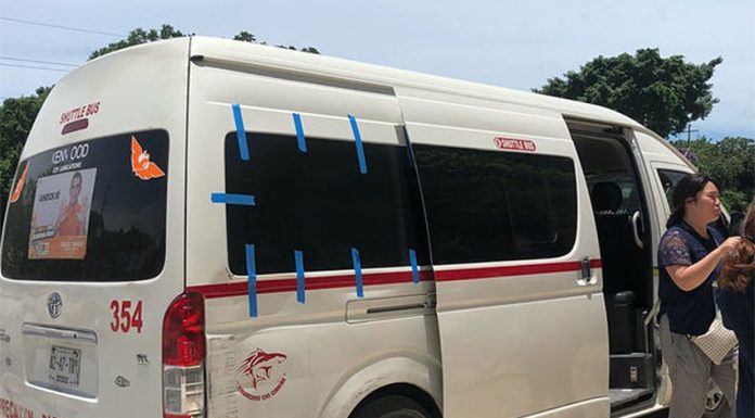 A white 15-passenger van in Tulum with people exiting it.