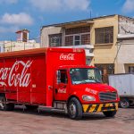 A Coca Cola distribution truck drives down a Mexican street