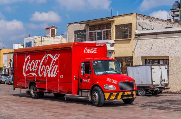 A Coca Cola distribution truck drives down a Mexican street