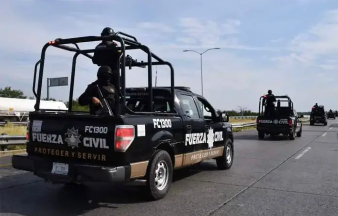 A convoy of several Nuevo León state police patrol vehicles drives down a highway