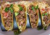 Four hard shell tacos with ground beef and shredded cheese, an example of Tex-Mex cuisine