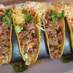 Four hard shell tacos with ground beef and shredded cheese, an example of Tex-Mex cuisine