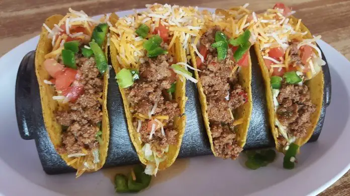 Four hard shell tacos with ground beef and shredded cheese, an example of Tex-Mex cuisine