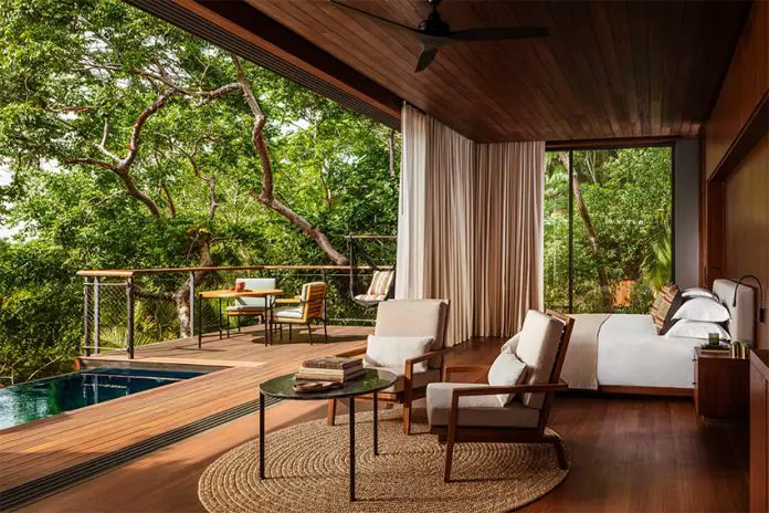 A hotel room opens into a balcony with a pool, just under the canopy of a rainforest.