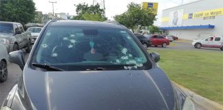 A car with multiple bullet holes in its windshield, stopped on the side of a street in Mazatlán, Sinaloa